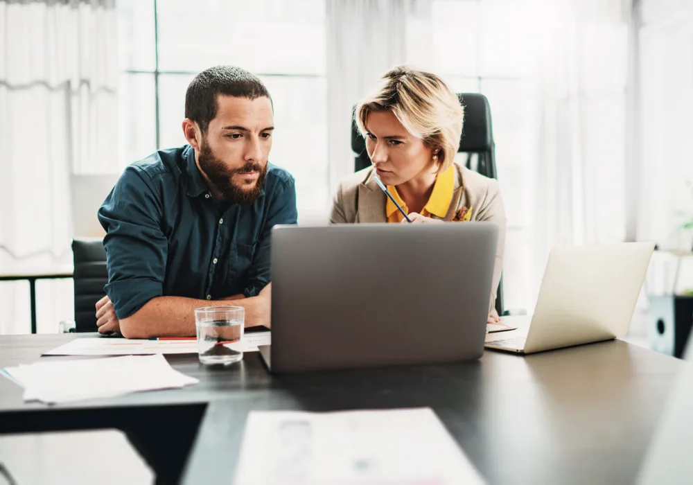 Ein Mann und eine Frau besprechen am Laptop die Datenanalyse und Betriebsoptimierung