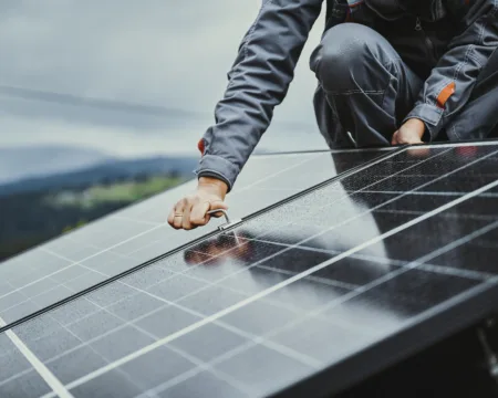 Ein Mitarbeiter montiert Solarpanels auf einem Hausdach