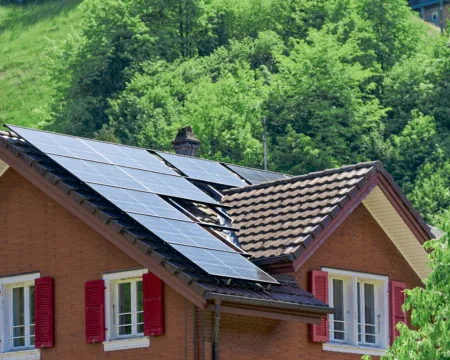 Solarpanels auf einem Hausdach. Das Haus hat rote Fensterläden und steht sinnbildlich für die verschiedenen Stromprodukte von ewl.