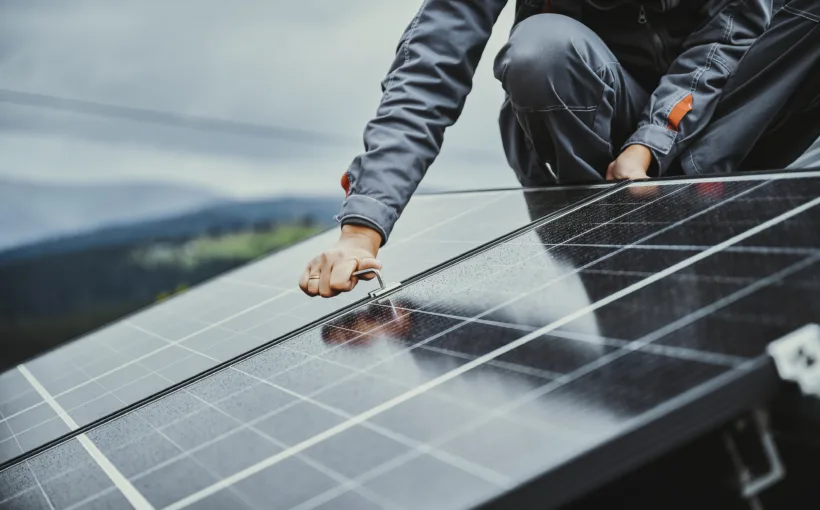 Ein Mitarbeiter montiert Solarpanels auf einem Hausdach