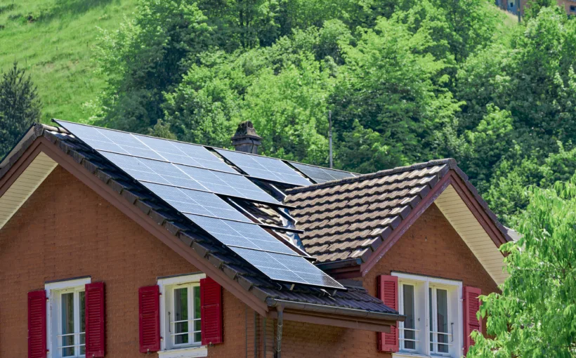 Solarpanels auf einem Hausdach. Das Haus hat rote Fensterläden und steht sinnbildlich für die verschiedenen Stromprodukte von ewl.